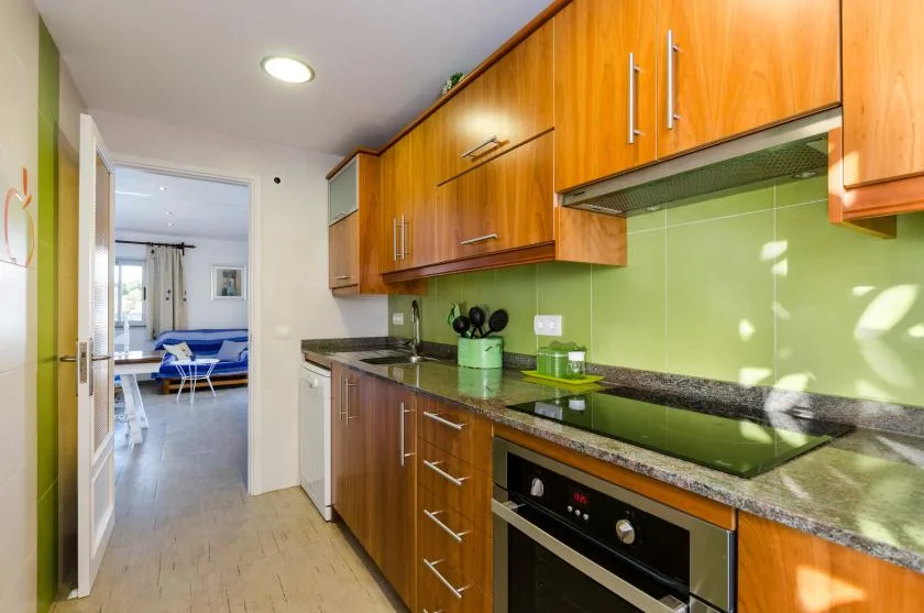 Una cocina con gabinetes de madera, una encimera oscura y un salpicadero verde.