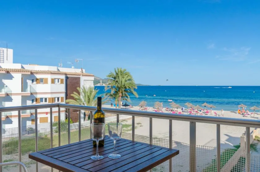 A balcony dining table overlooks a sandy beach and the sea.