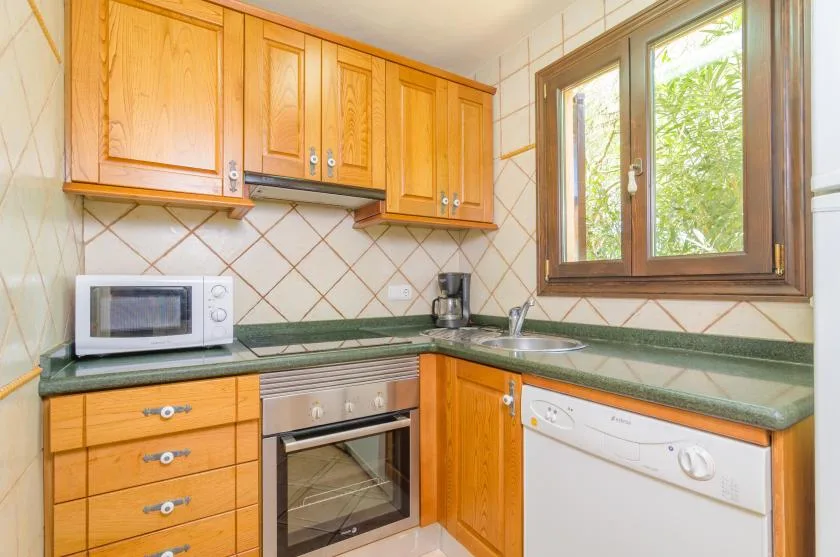 A kitchen with wooden cabinets, a green countertop, and a window.