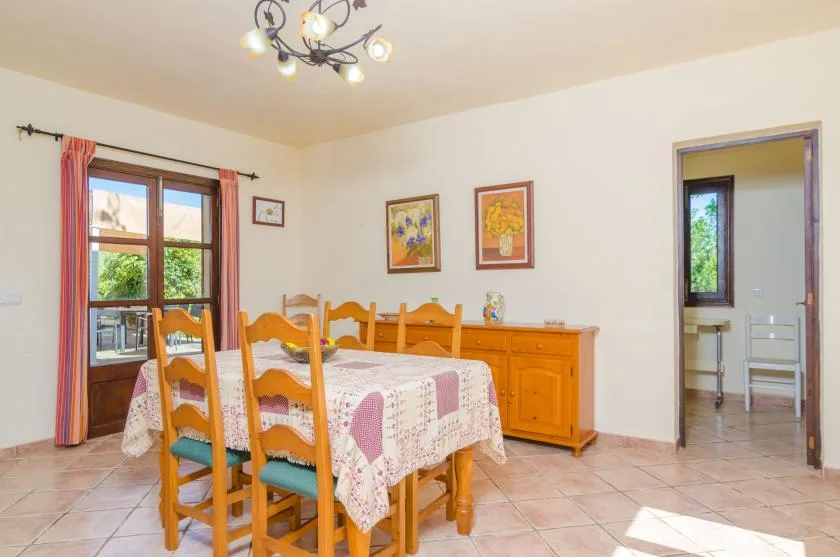 A dining room with a wooden table and chairs beside a sunny window.