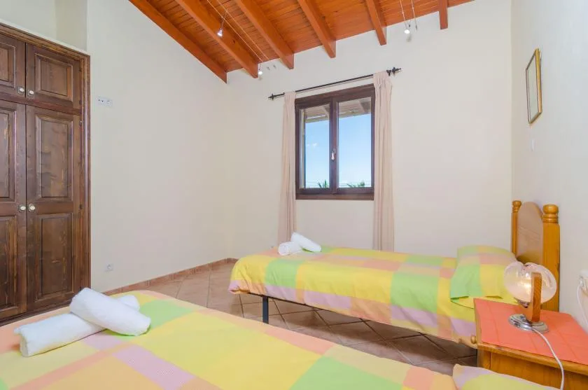 A bedroom with two beds covered in colorful striped bedding.