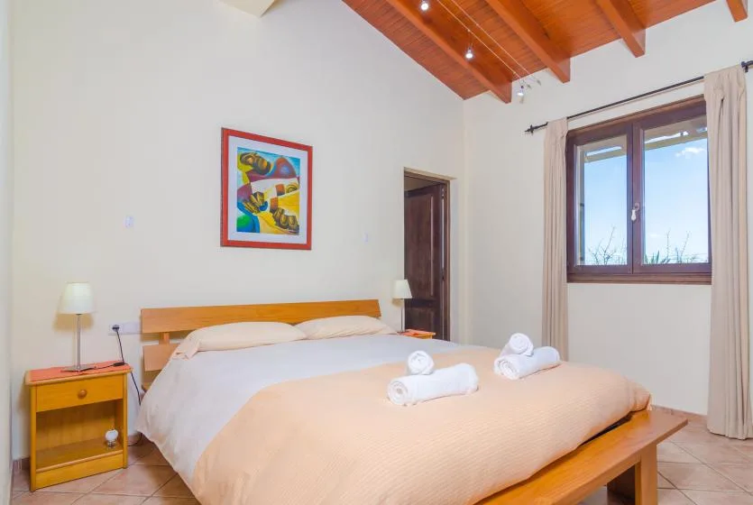 A bedroom with a large bed, colorful wall art, and a window.