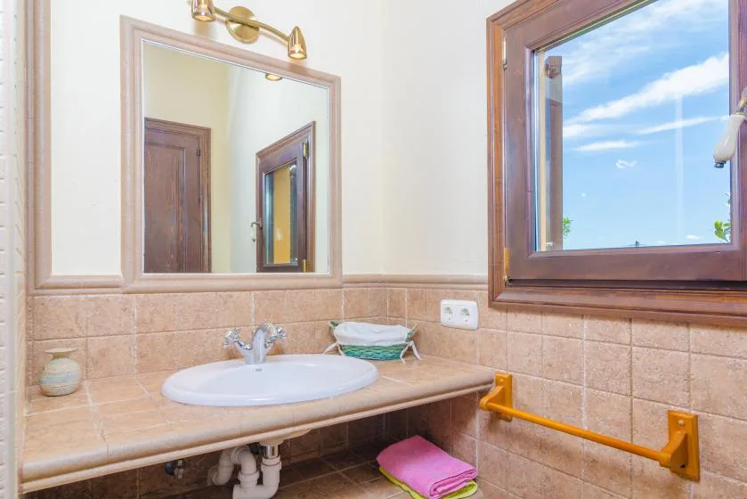 A bathroom vanity with a sink, wall mirror, and window.