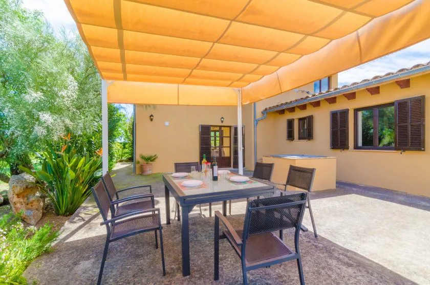 An outdoor dining area with a table and chairs beneath an orange canopy.