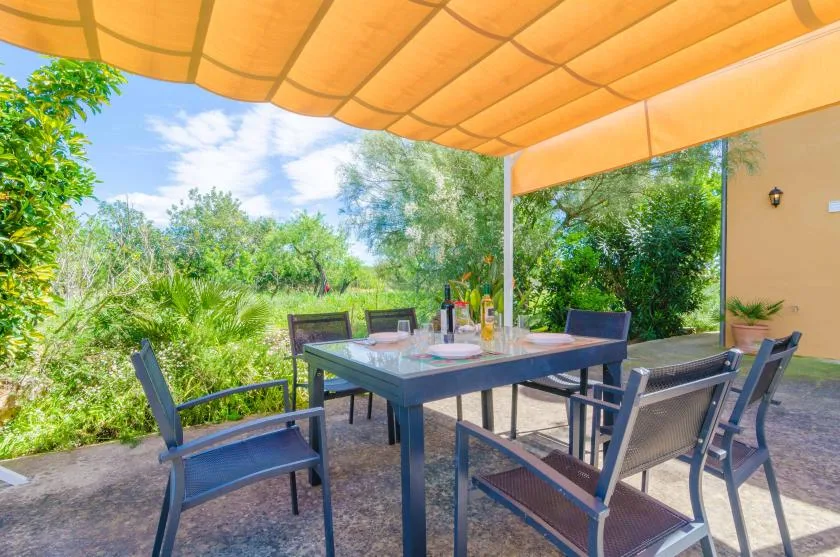 An outdoor dining area with a table and seating beneath an orange awning.