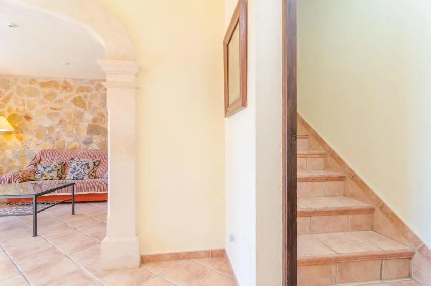 A tiled interior hallway opens onto a sitting area beside a staircase.