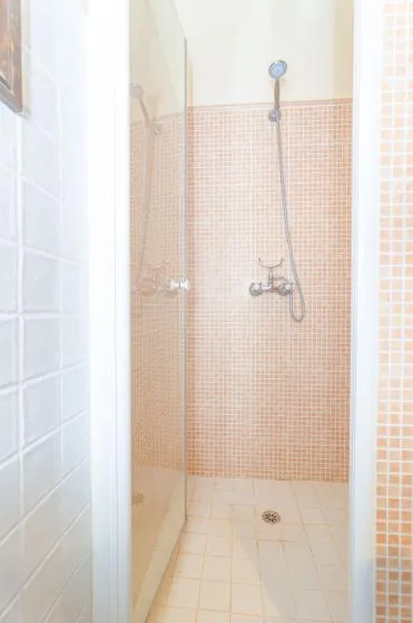 A tiled shower area with a handheld showerhead and floor drain.