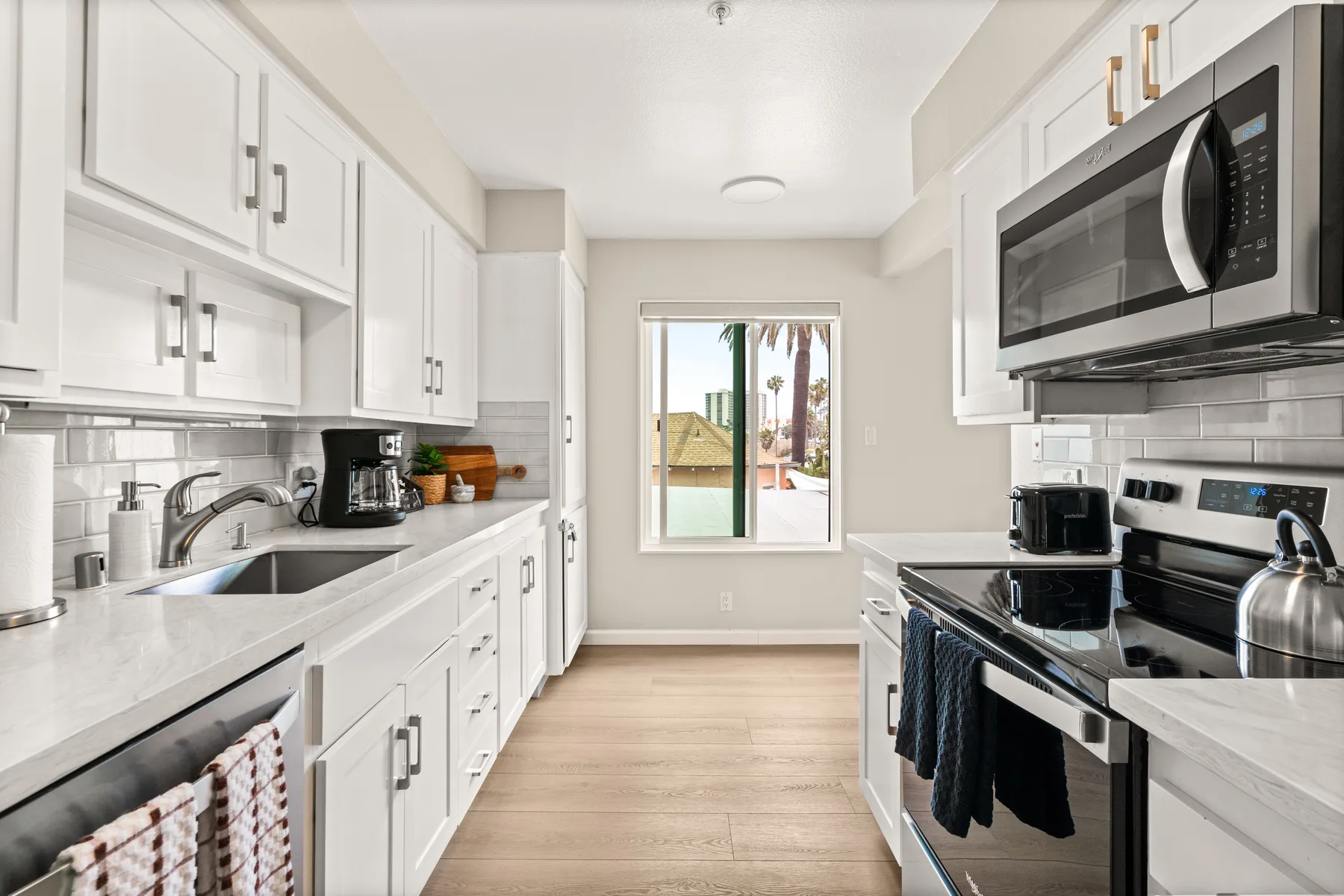 Una cocina luminosa con gabinetes blancos, encimeras y una ventana al fondo.