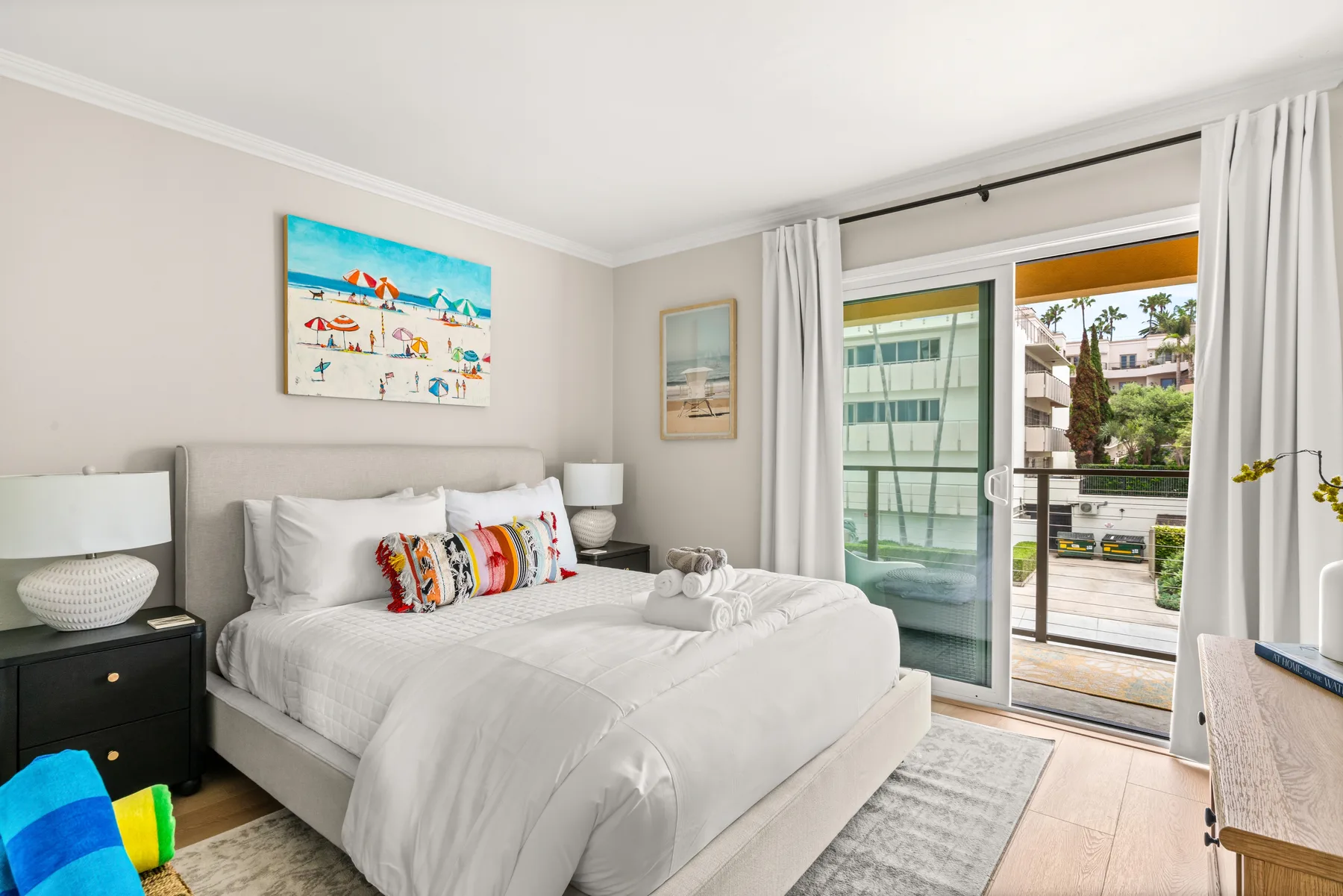 Un dormitorio con una cama tendida y puertas corredizas de vidrio que dan a un balcón.