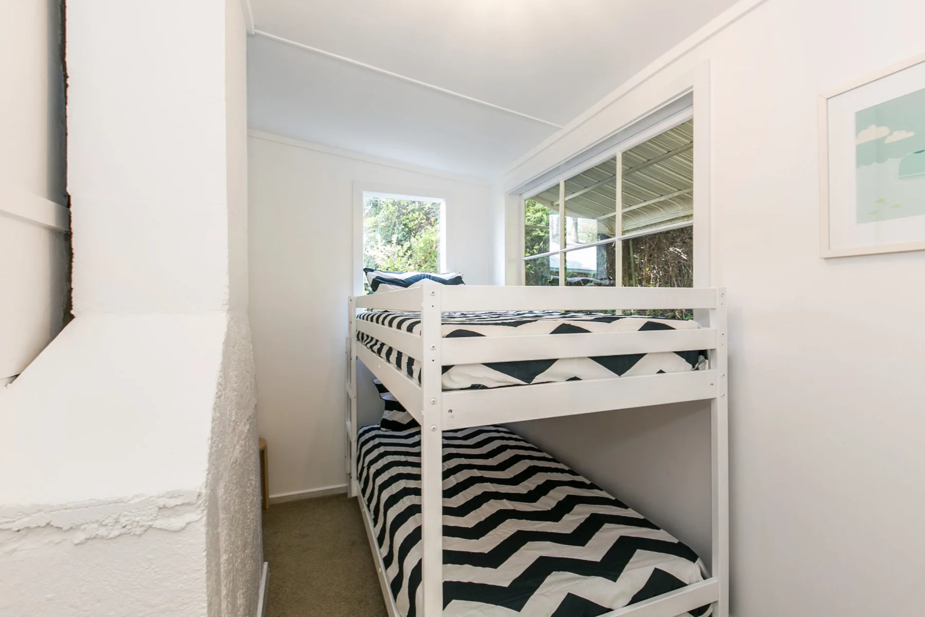 Un dormitorio luminoso con una litera y ropa de cama estampada en blanco y negro.