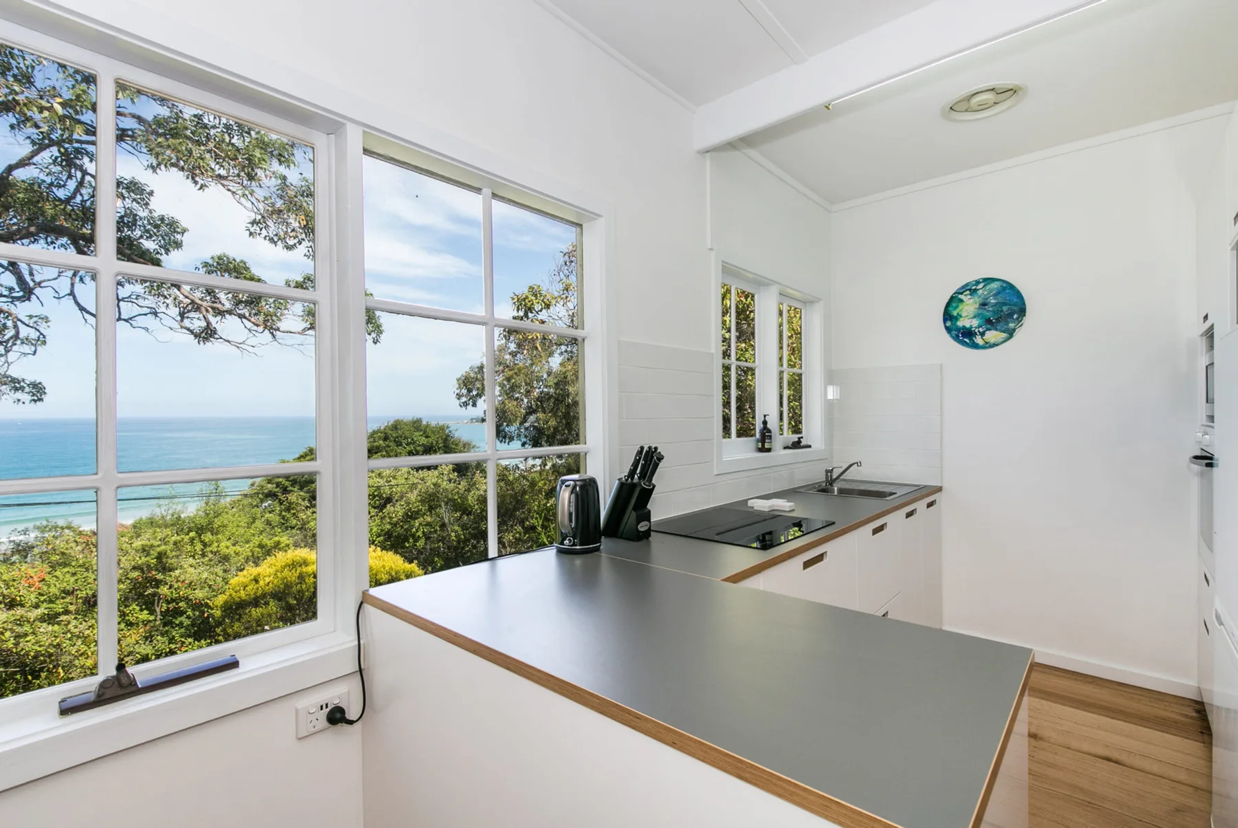 Una cocina luminosa con una encimera larga y grandes ventanas con vistas al agua.