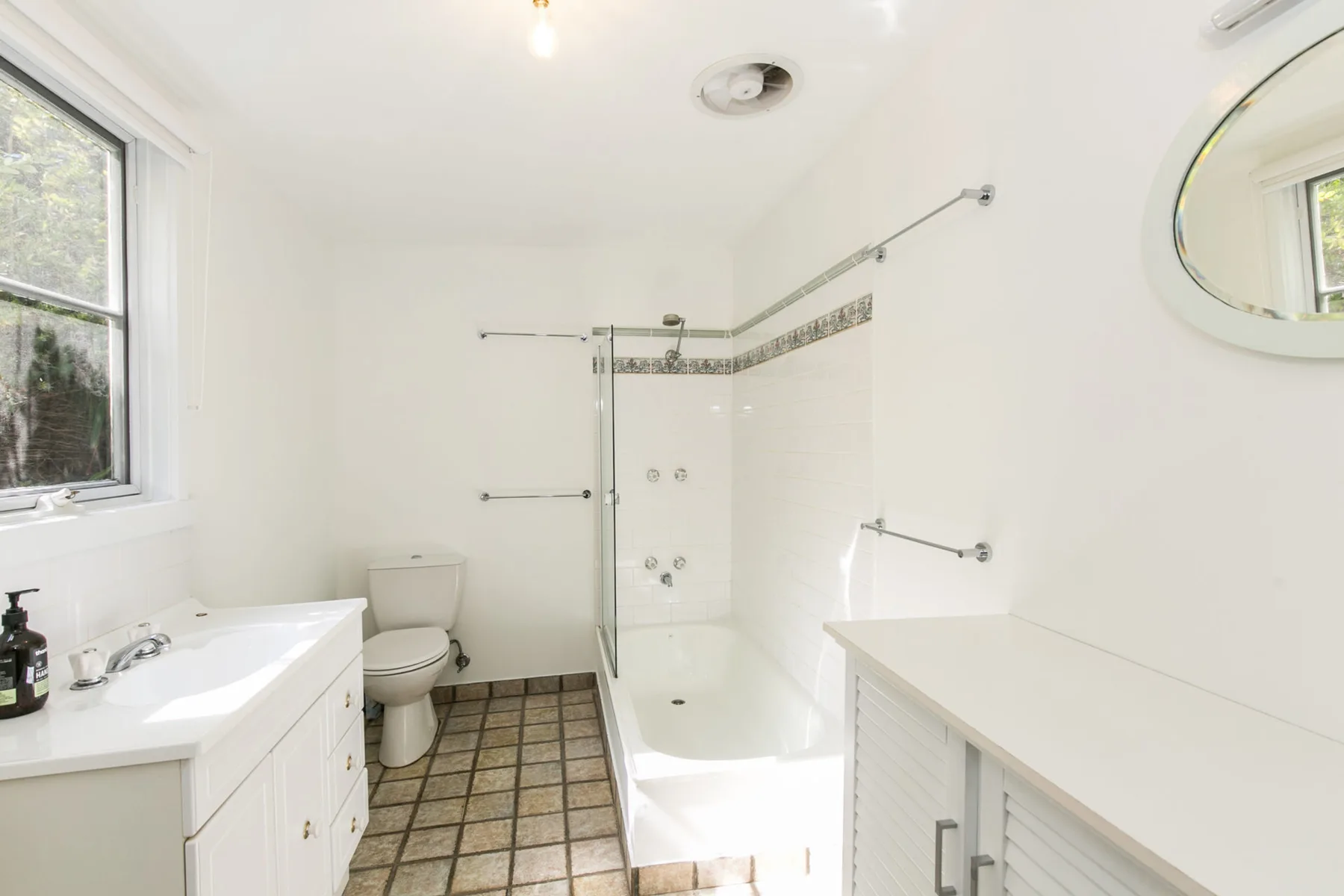 Un baño luminoso con bañera, lavabo y ventana.