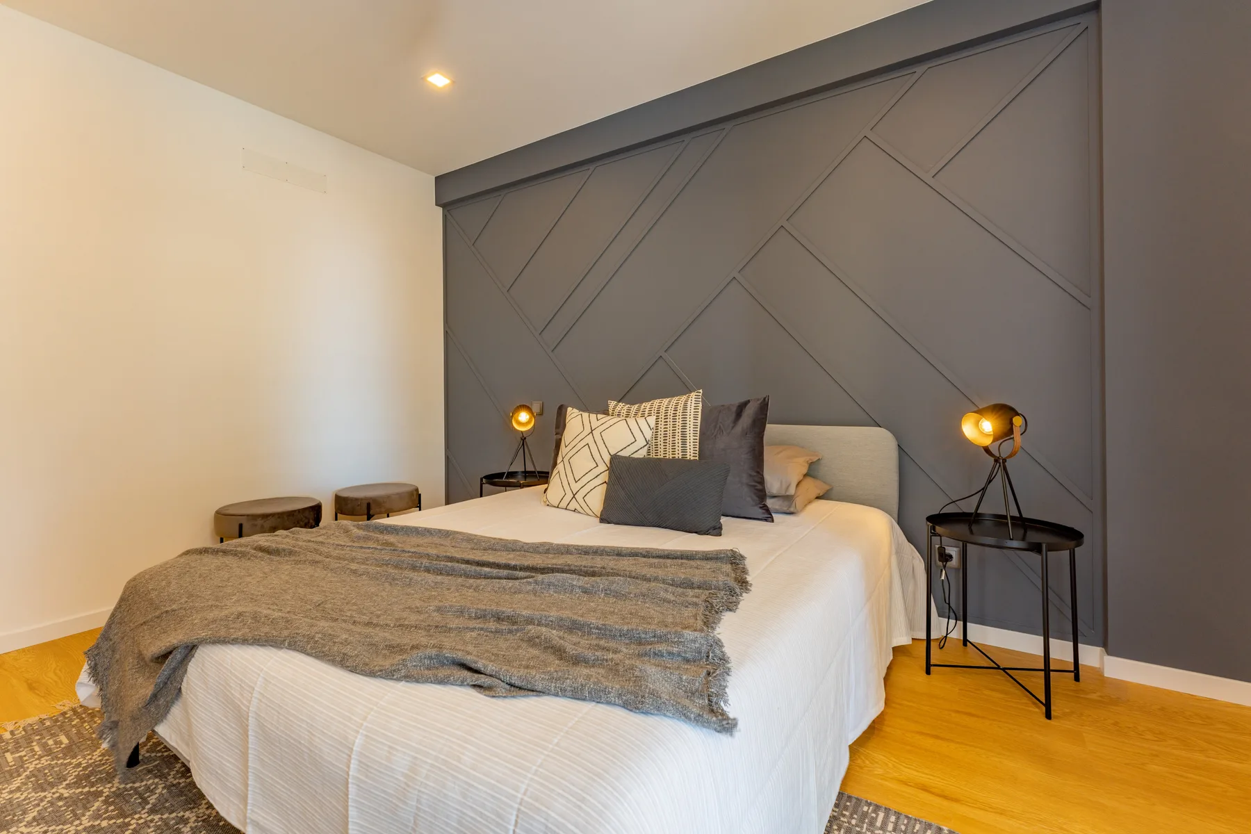 A bedroom with a bed against a dark geometric accent wall.