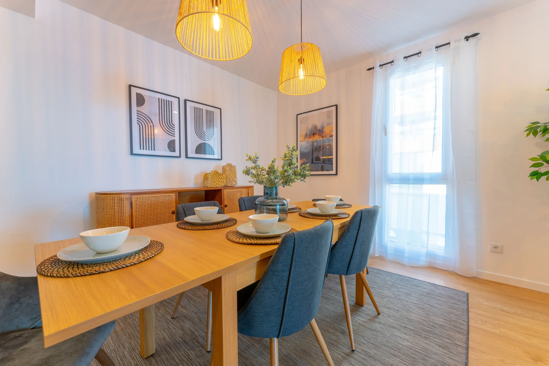 A dining area with a wooden table, blue seating, and a window.
