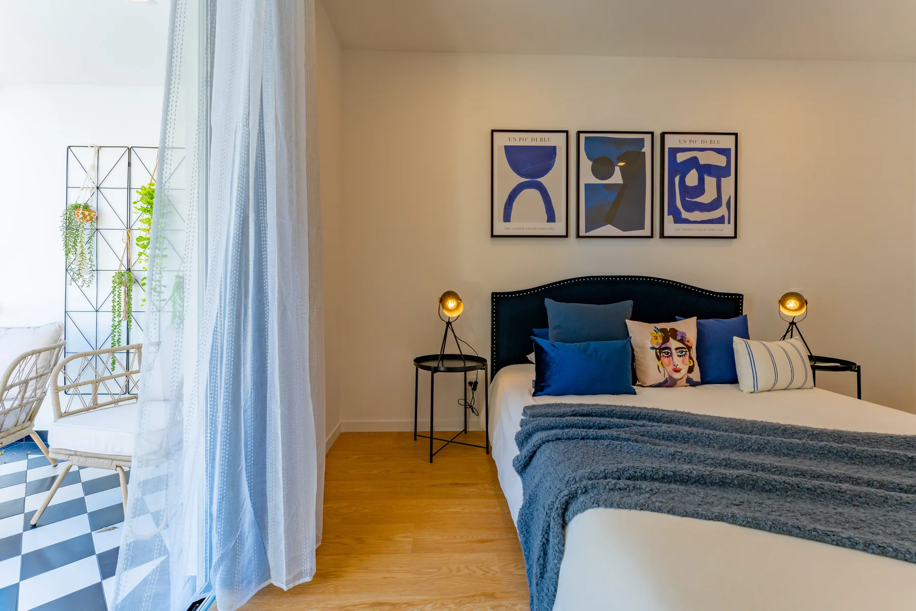 A bedroom with a bed, bedside tables, and framed artwork above the headboard.