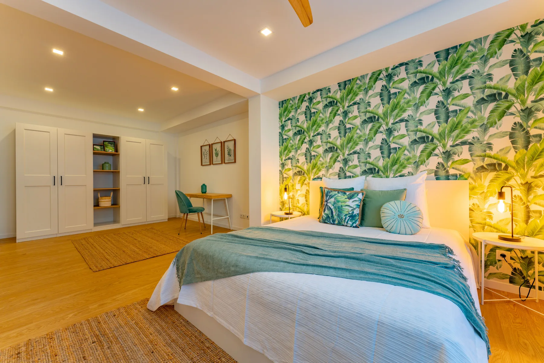 A bedroom with a bed, leafy wallpaper, and built-in storage.