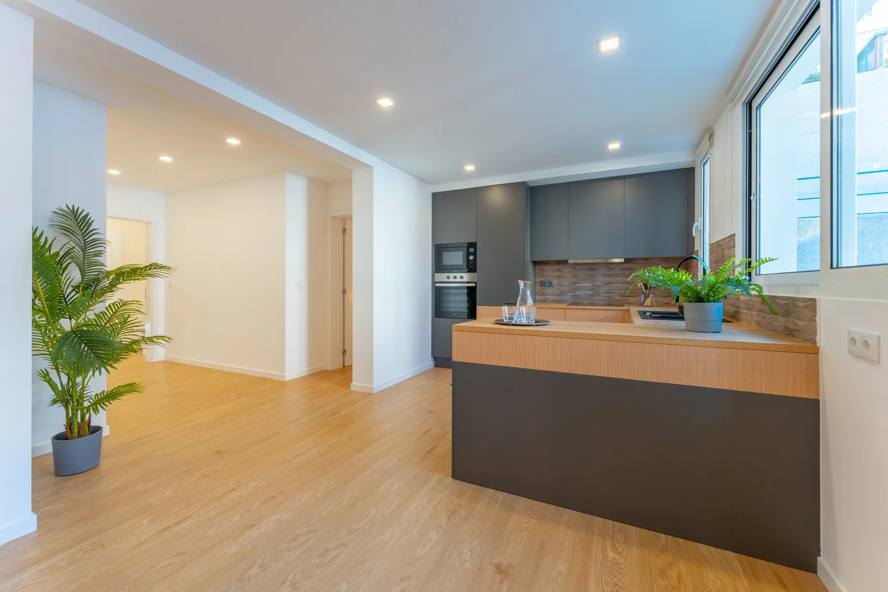 An open-plan kitchen and living area with a wide island and large windows.