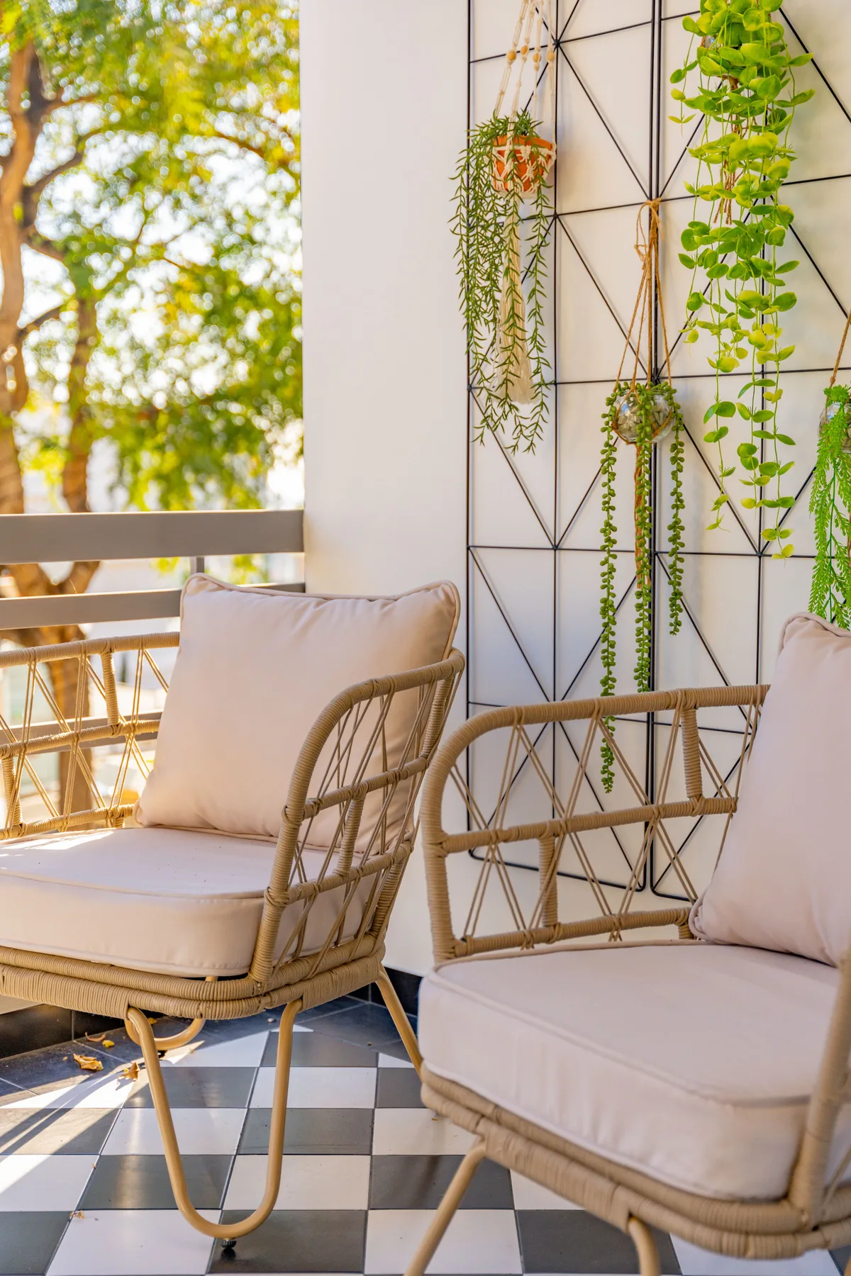 A balcony seating area with cushioned chairs and hanging plants.