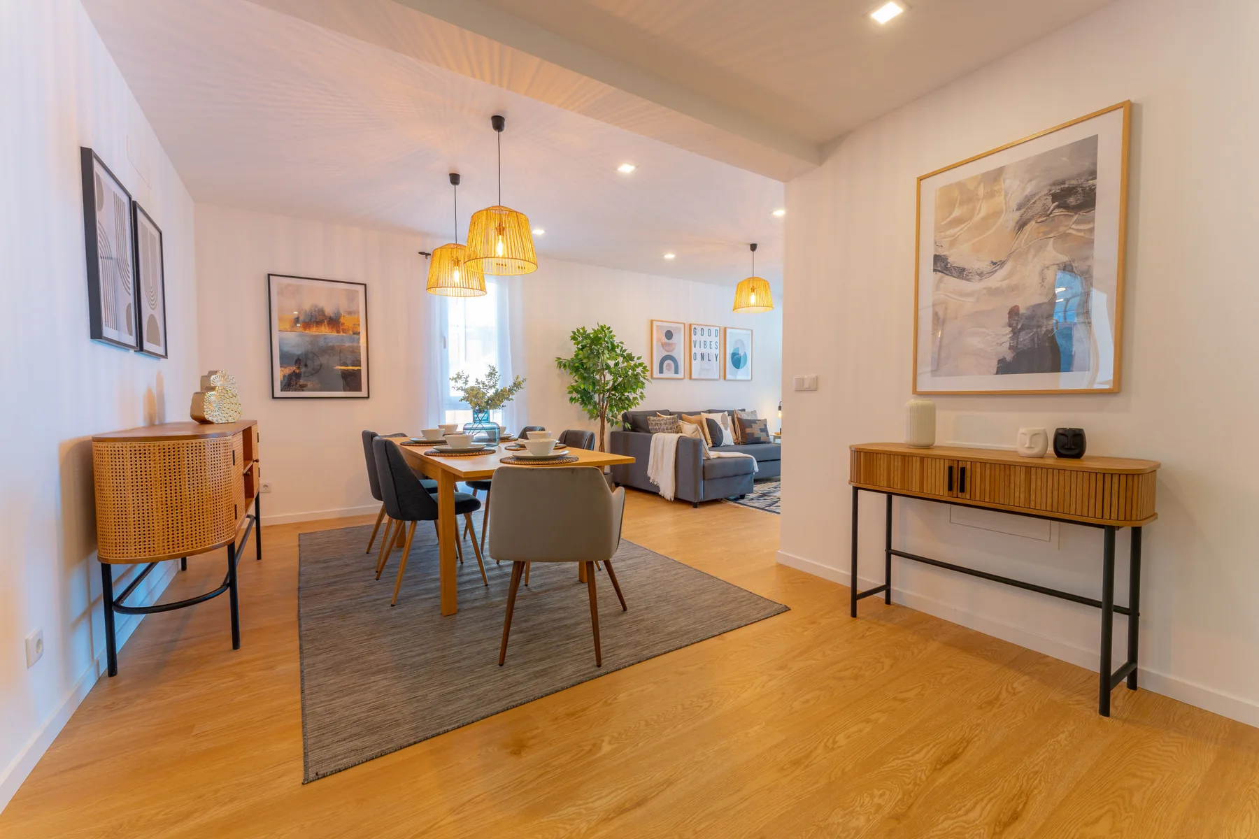 A bright dining and living area with a table, seating, and framed wall art.