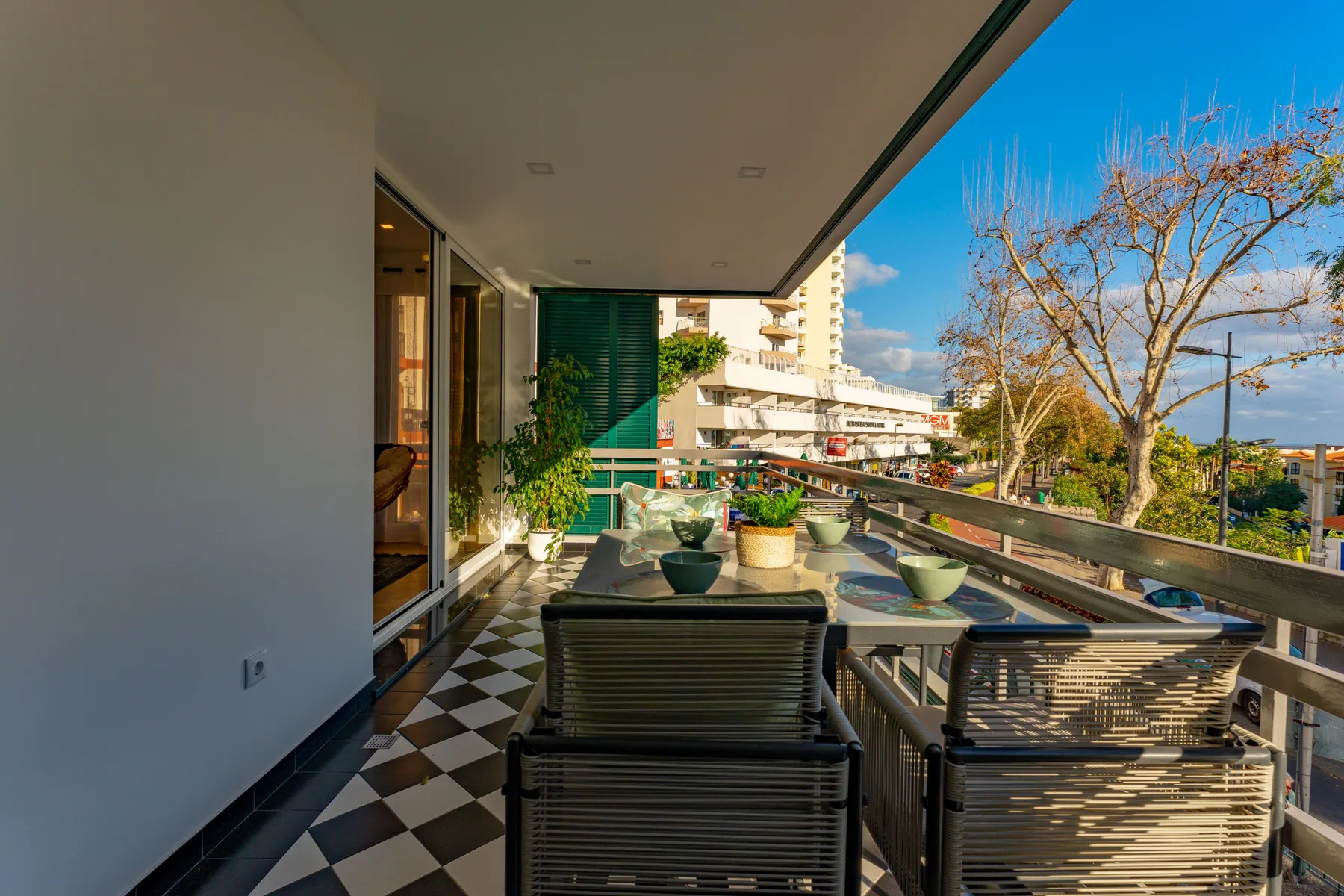 Una terraza con asientos y plantas en macetas ofrece vistas de edificios cercanos.