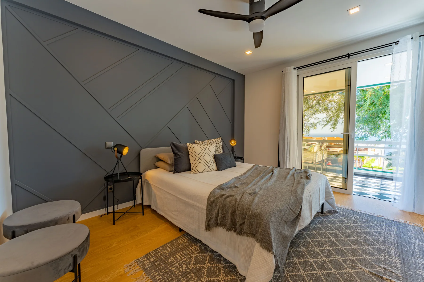 A bedroom with a bed and sliding glass doors opening onto a balcony.
