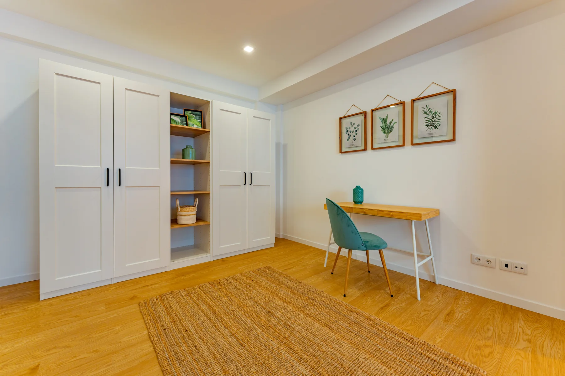 A bright room with built-in storage, a small table, and a woven rug.