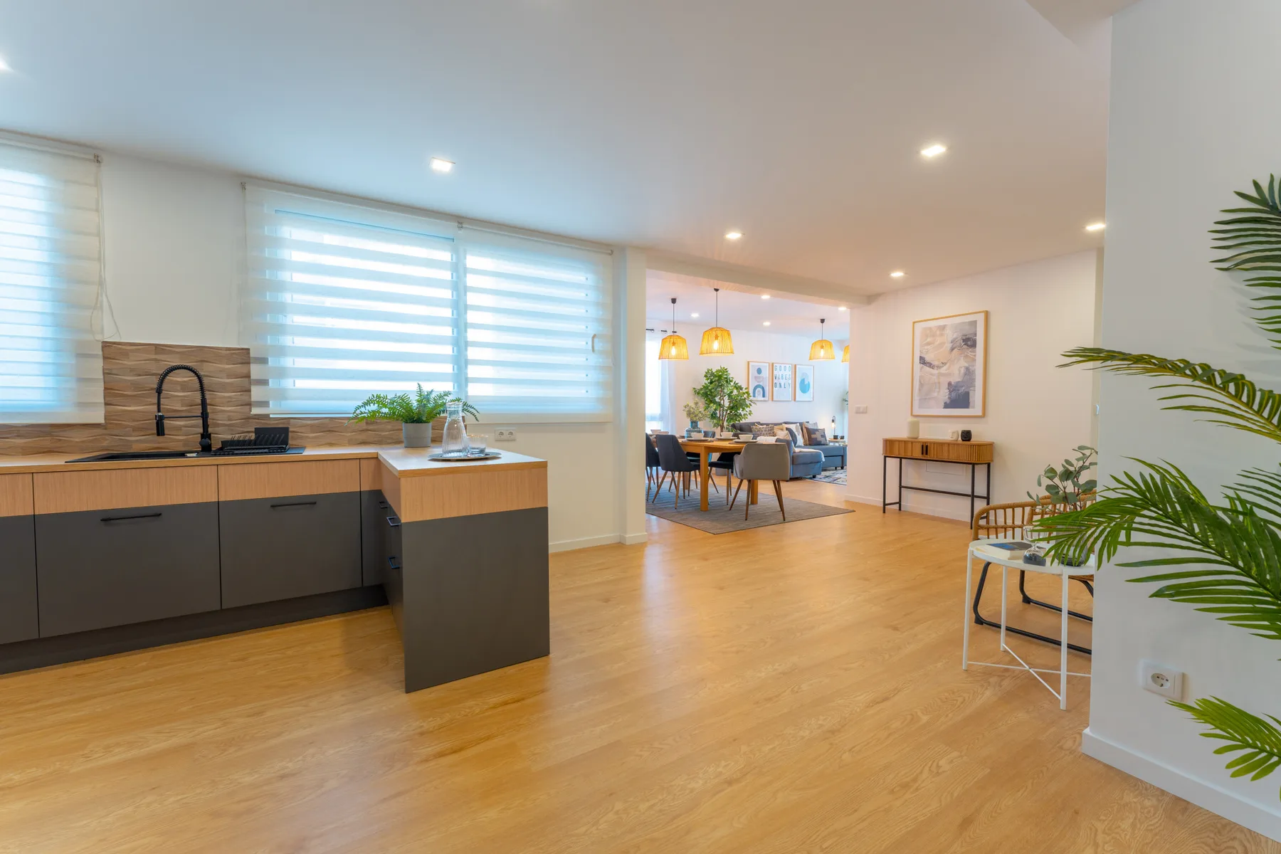 Open-plan kitchen and dining area with light wood flooring and large windows.