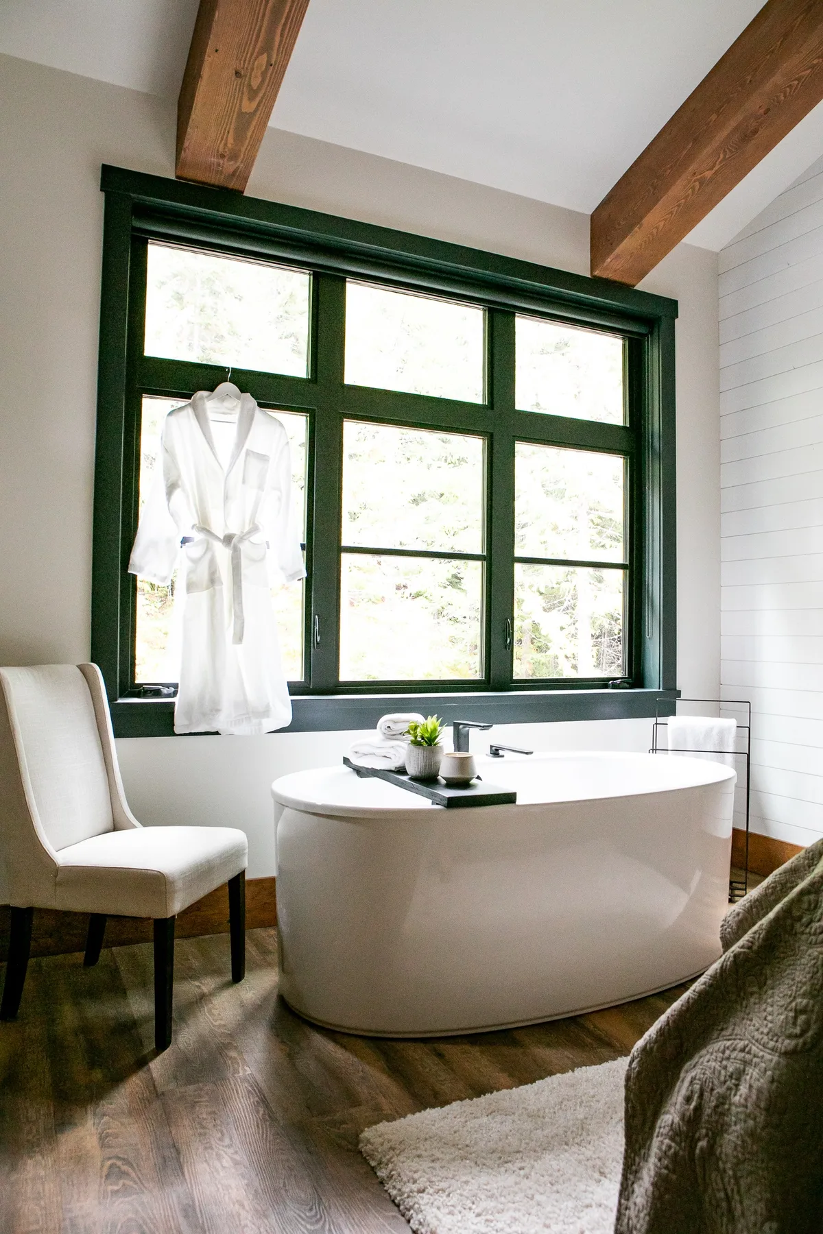 Un baño con una bañera exenta bajo una ventana grande.
