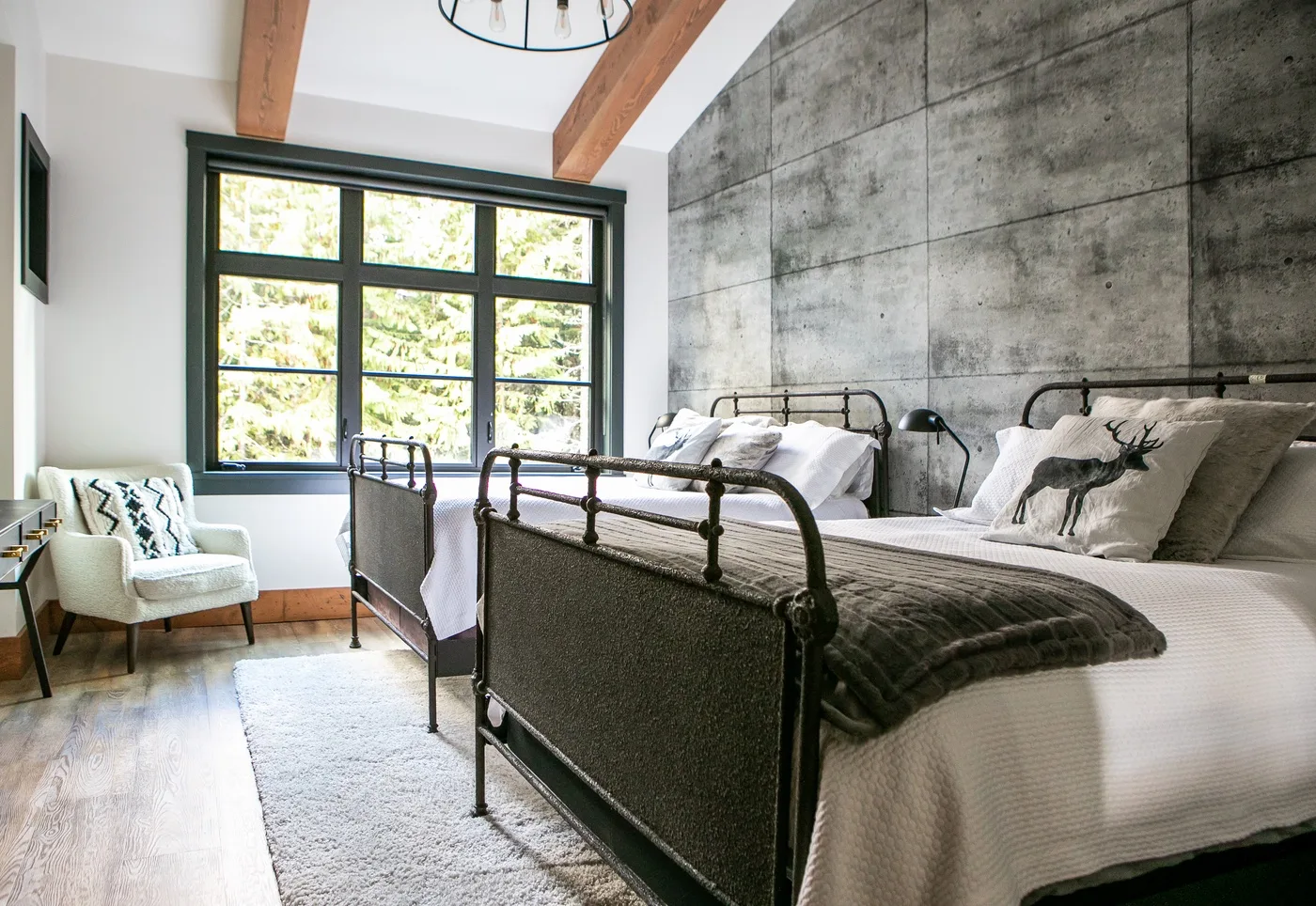 Dormitorio luminoso con camas de metal, una ventana grande y una zona de estar.