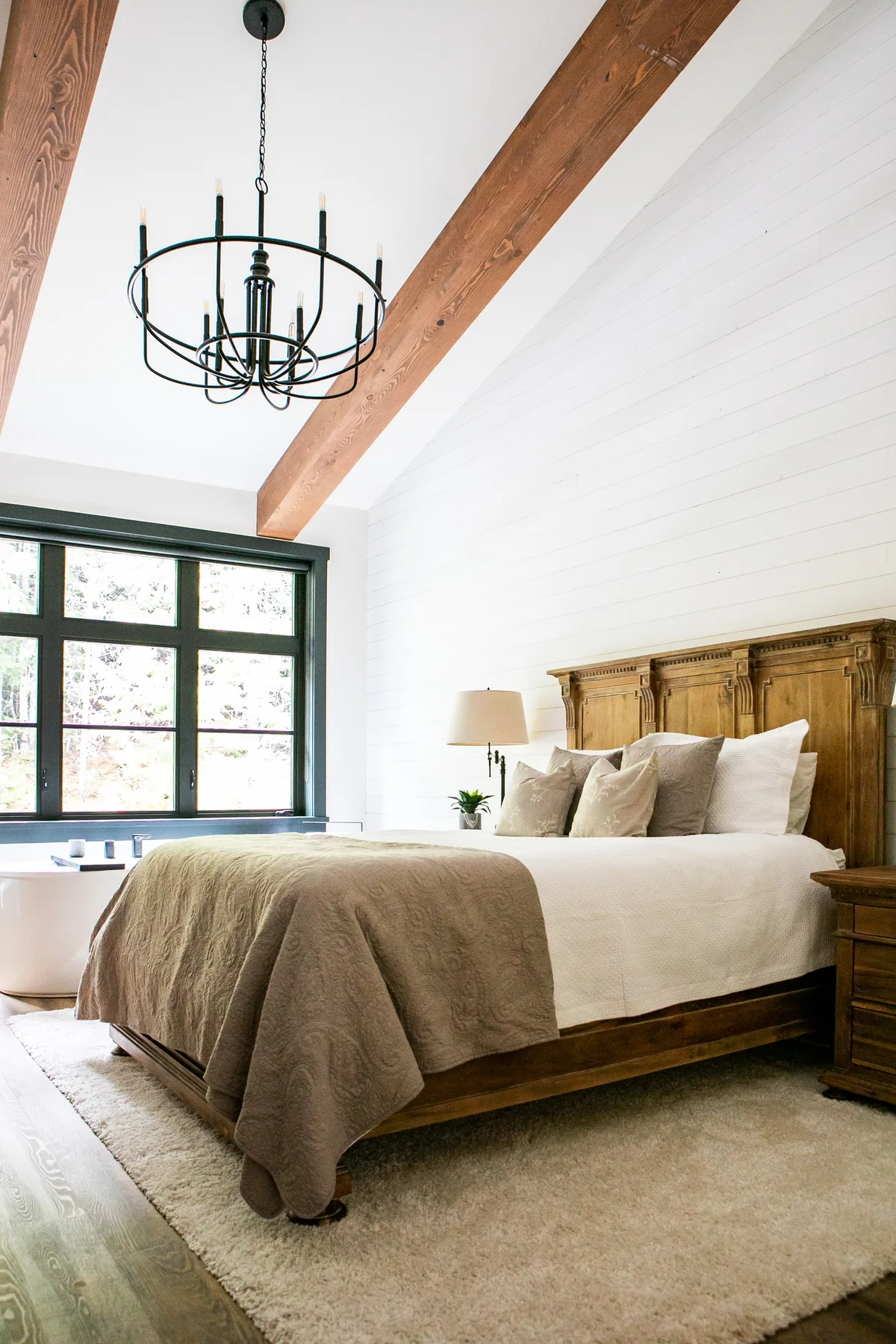 Un dormitorio luminoso con una cama grande bajo un techo con vigas de madera.