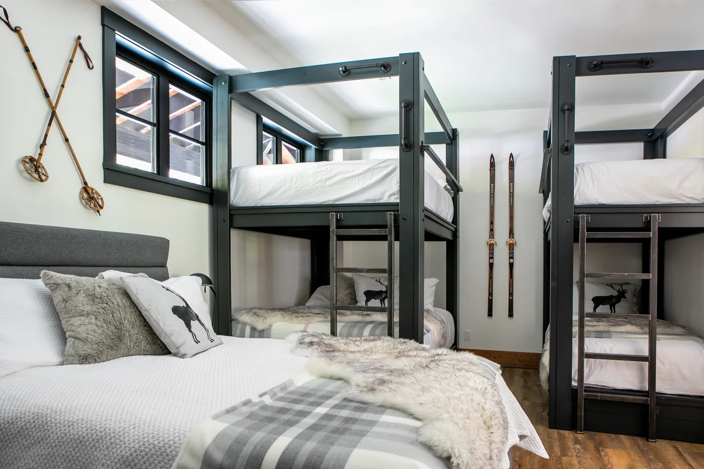 Un dormitorio con literas, camas bien tendidas y esquís en la pared.