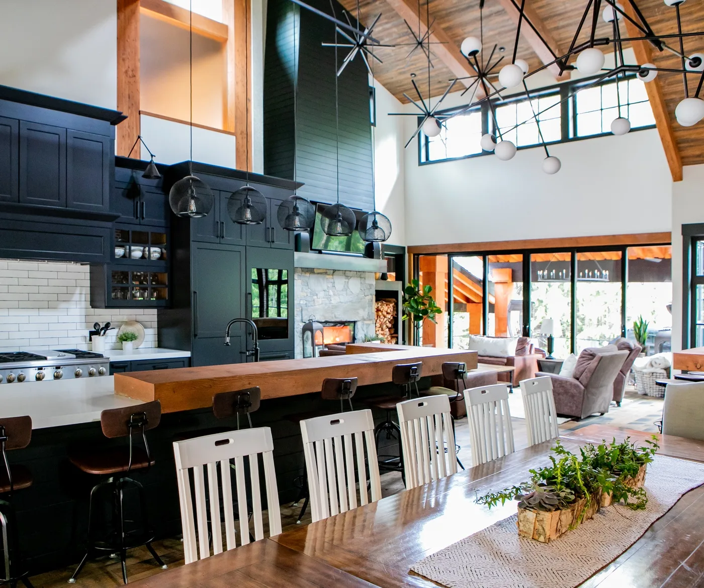 Una cocina y comedor de planta abierta tienen una mesa larga y ventanas luminosas.