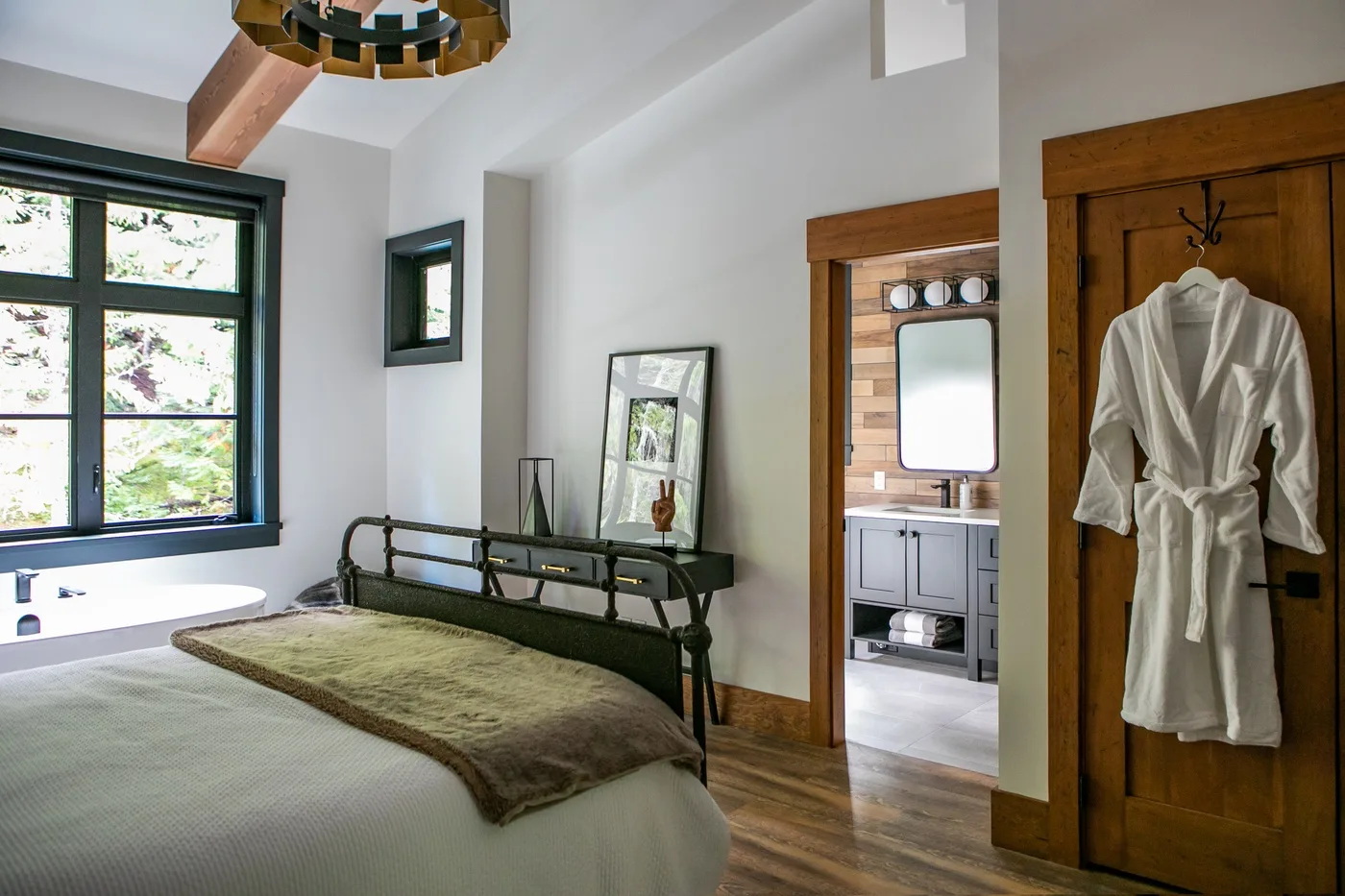 Un dormitorio con una cama, una ventana grande y un baño contiguo.