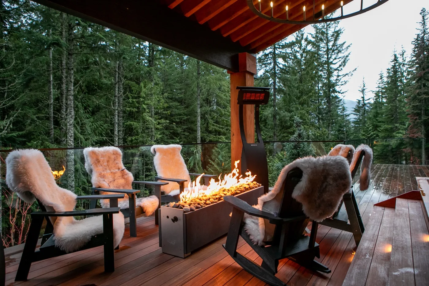 Una terraza exterior cubierta con asientos acolchados alrededor de una larga chimenea.