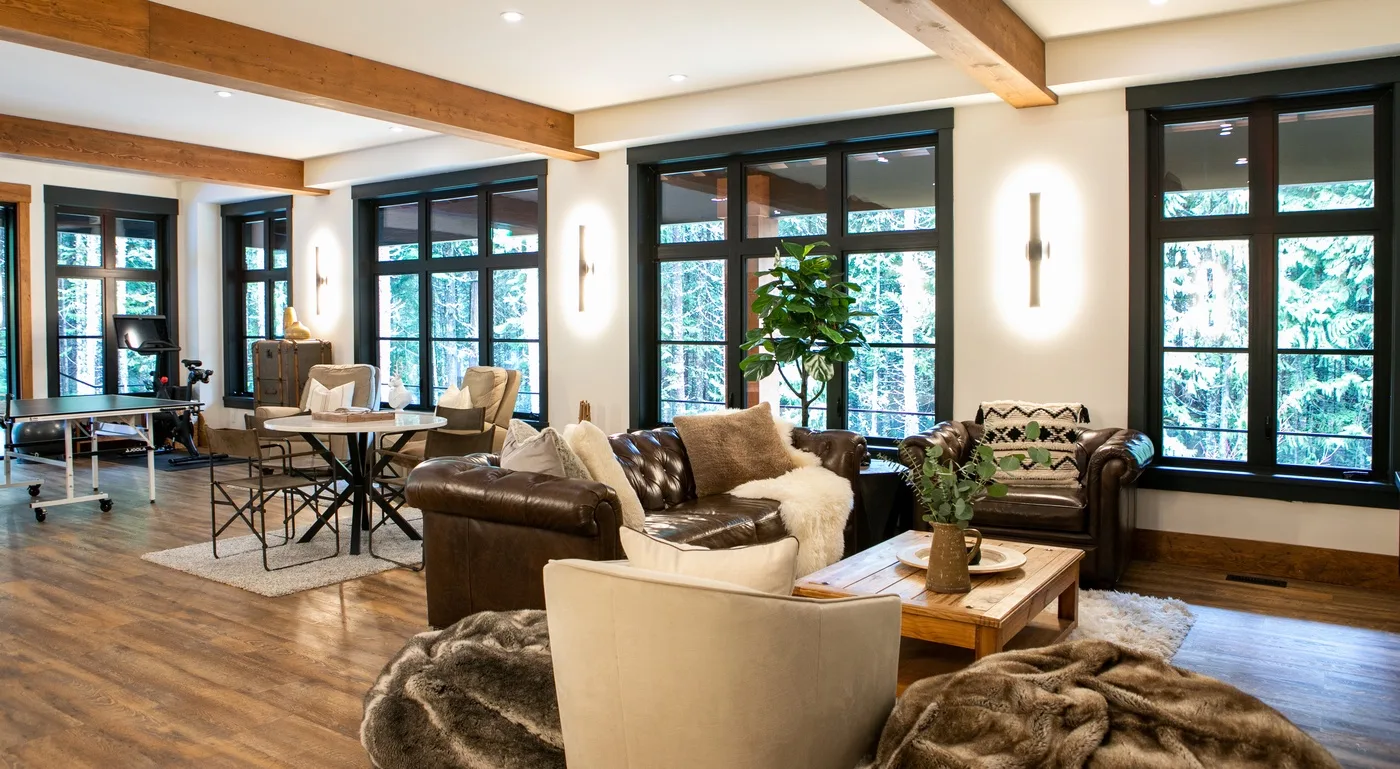 Una sala luminosa con asientos alrededor de una mesa de centro de madera y grandes ventanas.