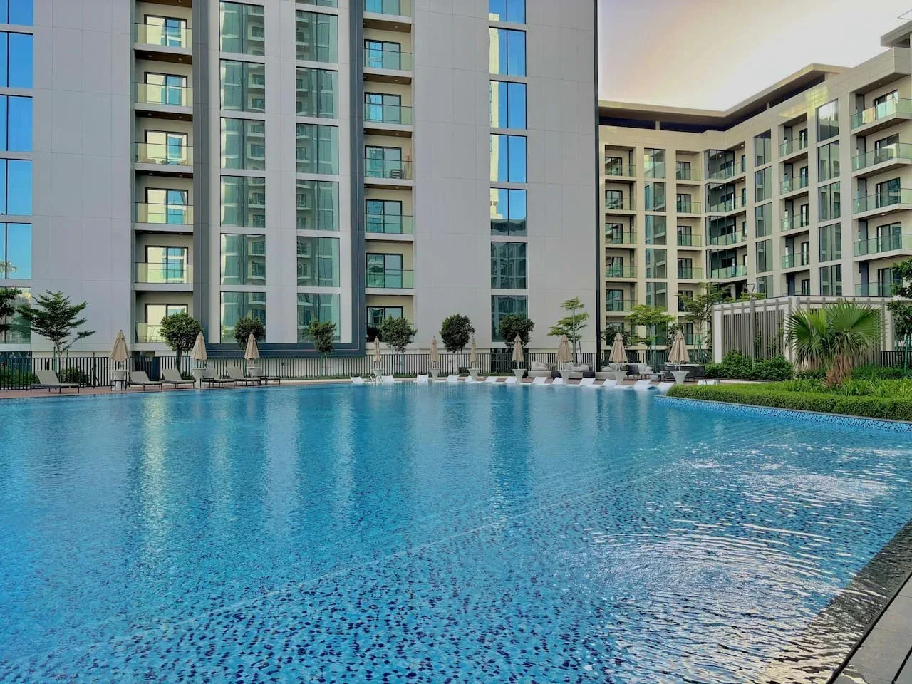 Una piscina está frente a un edificio moderno de varios pisos.