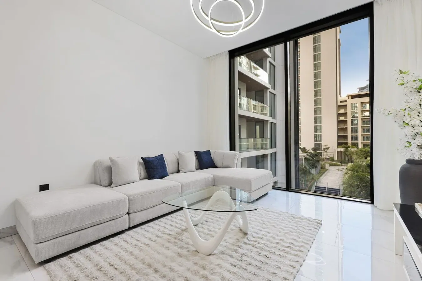 Una sala luminosa con asientos en forma de L junto a ventanales de piso a techo.
