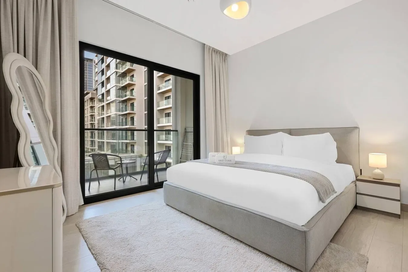 A bright bedroom with a neatly made bed beside a large glass door.