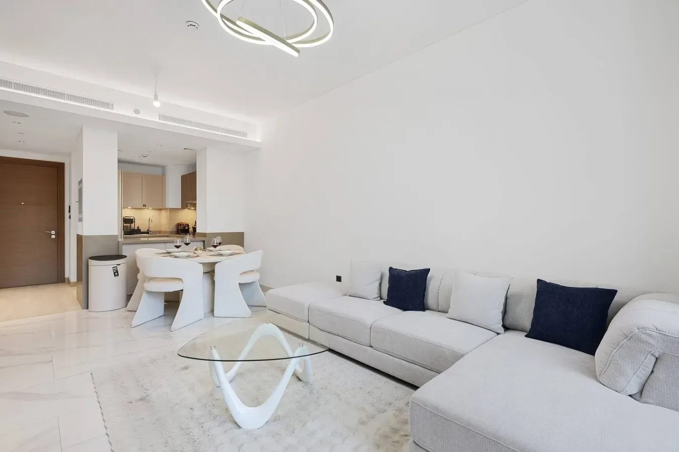 Una sala moderna con un sofá seccional claro y una mesa de centro de vidrio.