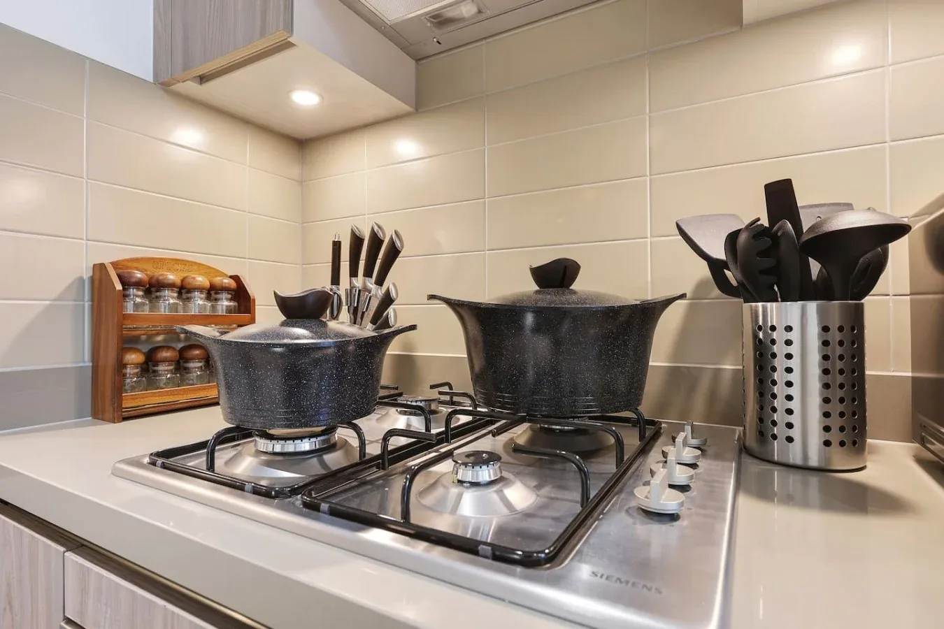 Una cocina con una estufa, utensilios de cocina y un porta utensilios sobre la encimera.
