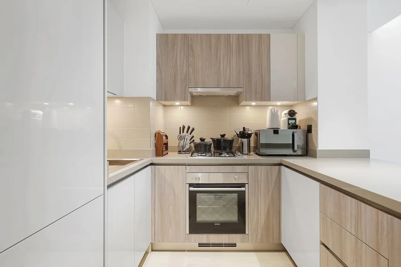 Una cocina moderna con gabinetes de acabado de madera, una placa de cocción y un horno.