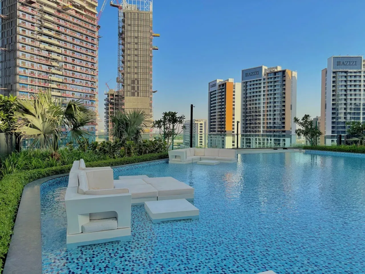 Una piscina en la azotea con asientos integrados da a edificios altos cercanos.