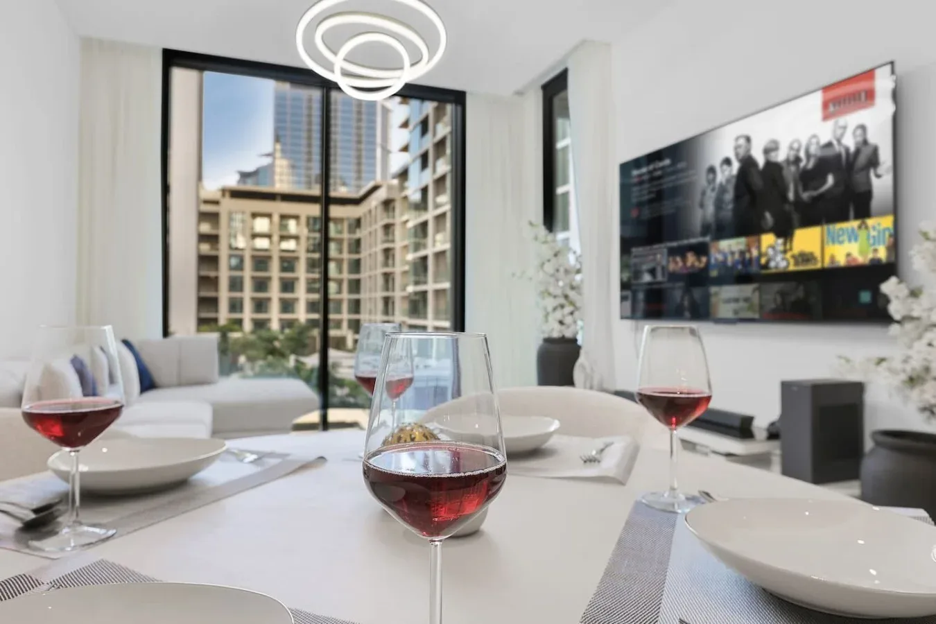 Un comedor con la mesa puesta, copas de vino y una ventana grande.