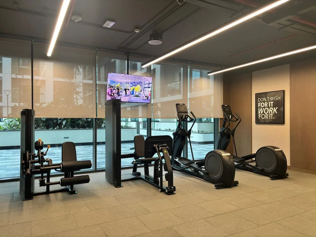 Un gimnasio con máquinas de ejercicio y grandes ventanales.