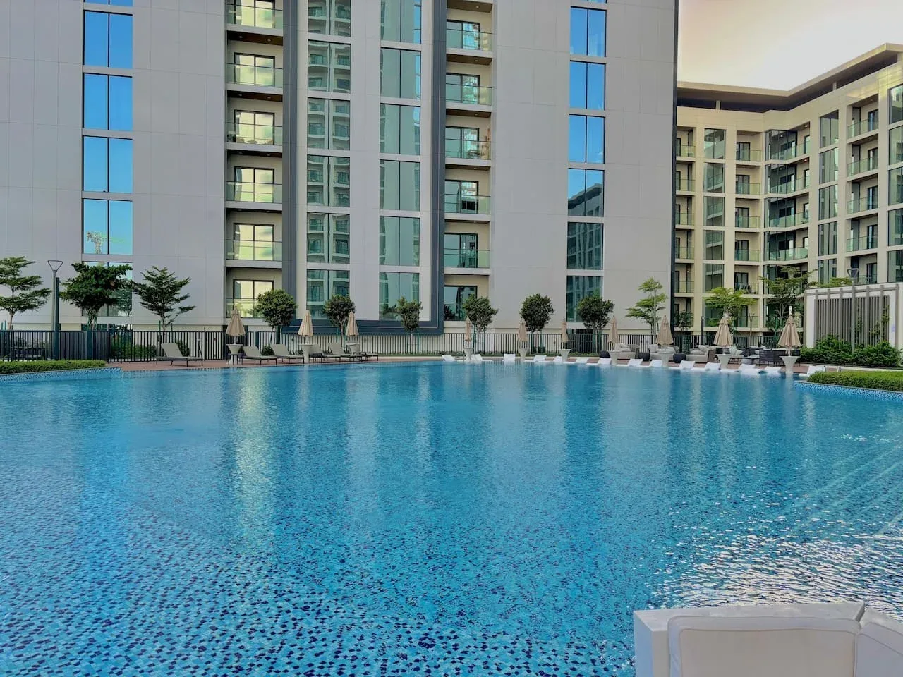 Una gran piscina al aire libre se encuentra frente a un edificio de apartamentos moderno.