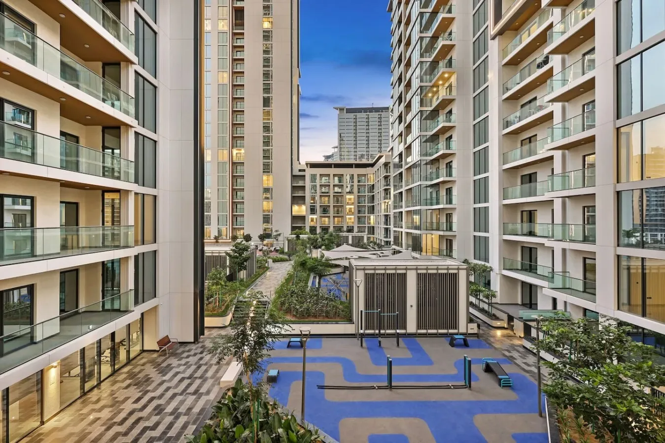 A landscaped courtyard with a blue recreation area between apartment buildings.