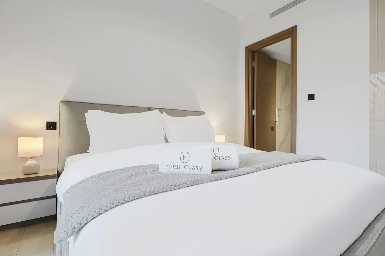 Un dormitorio con una cama bien tendida y lámparas de noche.