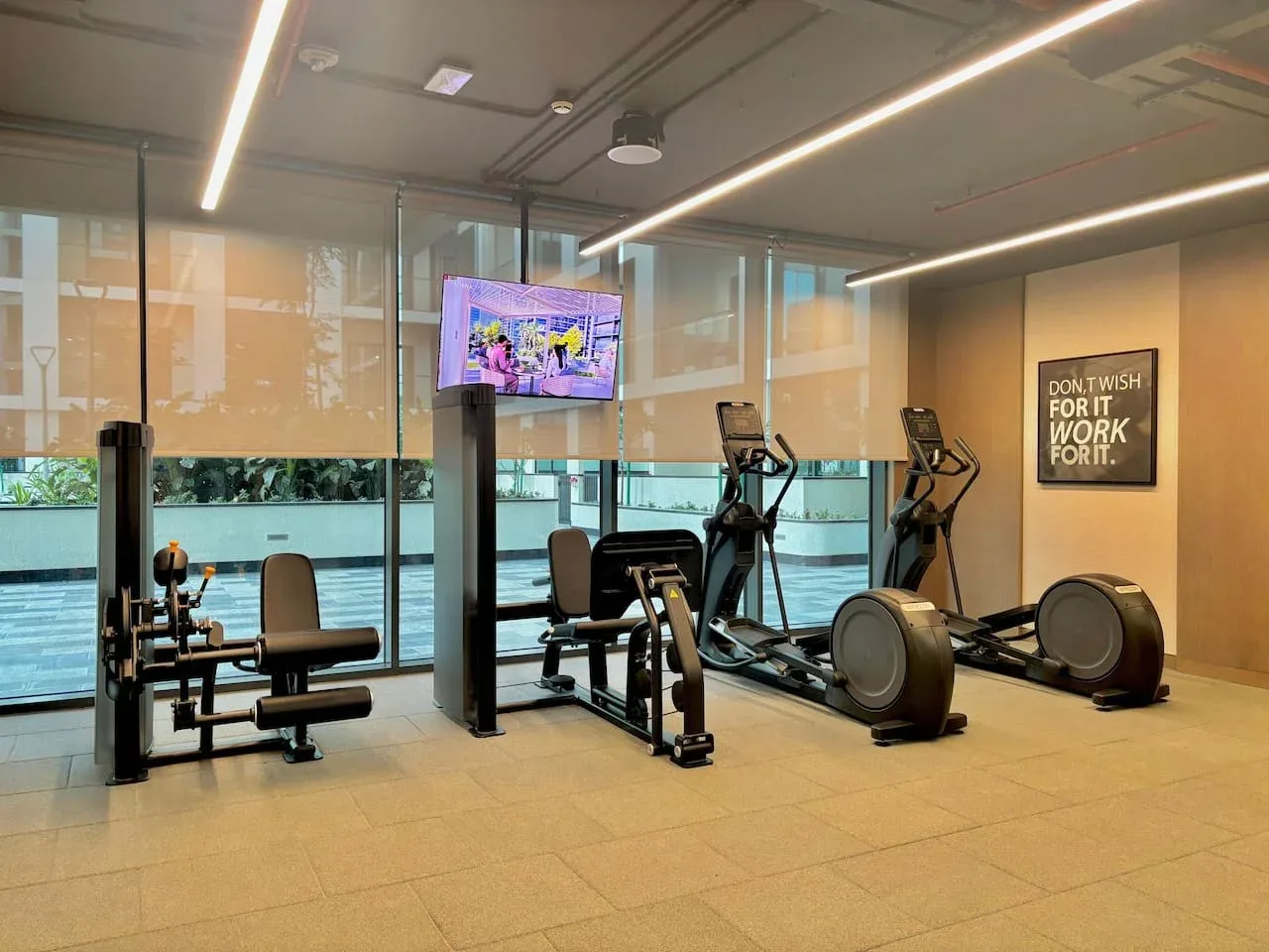 Un gimnasio con máquinas de ejercicio y grandes ventanas con vista al agua.