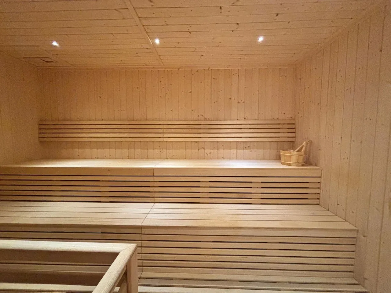 Una sauna revestida de madera con bancos escalonados e iluminación cálida.
