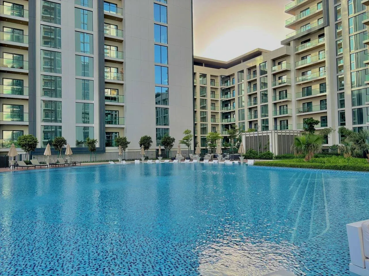 Una piscina al aire libre está junto a un edificio moderno de varios pisos.